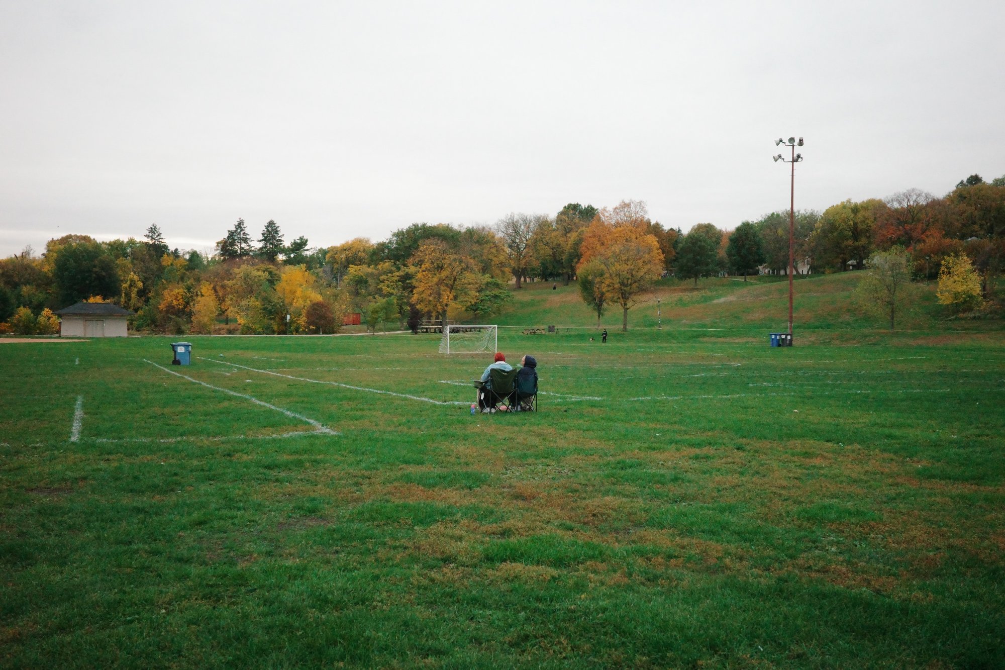 People sitting in the middle of the soccer field at Powderhorn Park Minneapolis